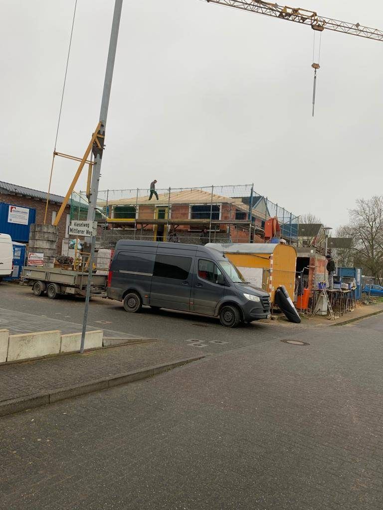 Autokran und Transporter vor einem eingerüsteten Wohnhaus in einer Wohnstraße
