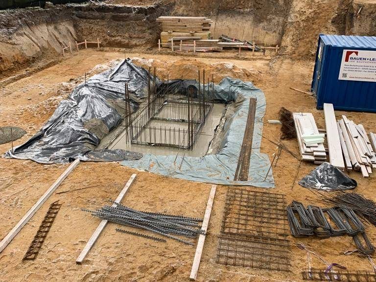 Ausgehobene Baugrube mit vorbereiteten Bewehrungskörben für Einzelfundamente