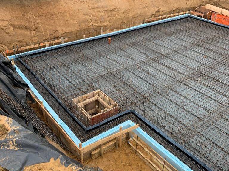 Umlaufendes Streifenfundament mit blauer Perimeterdämmung und ausgelegter Bewehrung