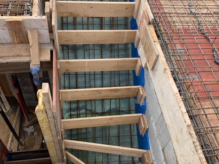 Hölzerne Schalung einer Betontreppe zwischen zwei Geschossen eines Rohbaus